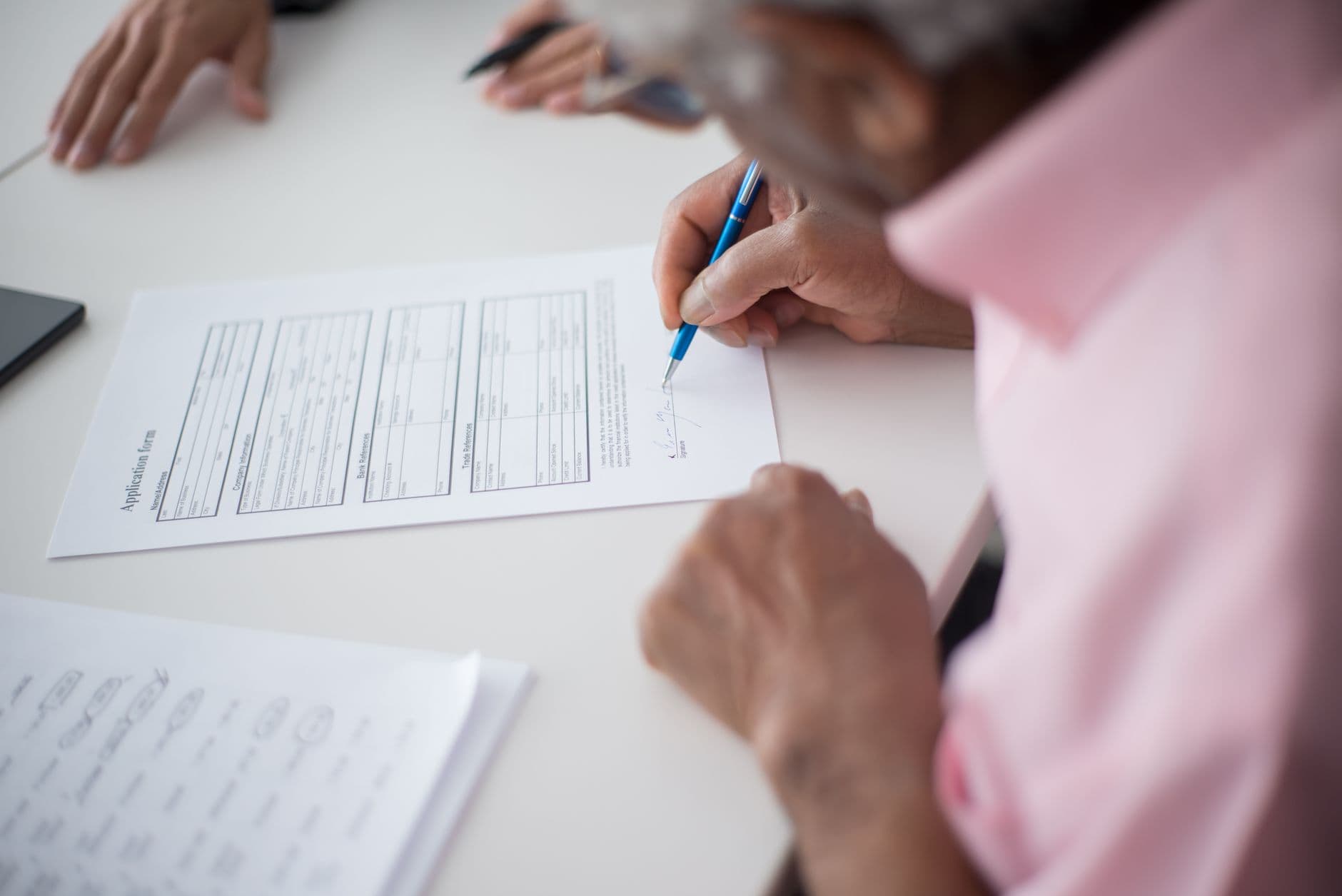 Young person signing an application form at a government office counter, learner driving permit